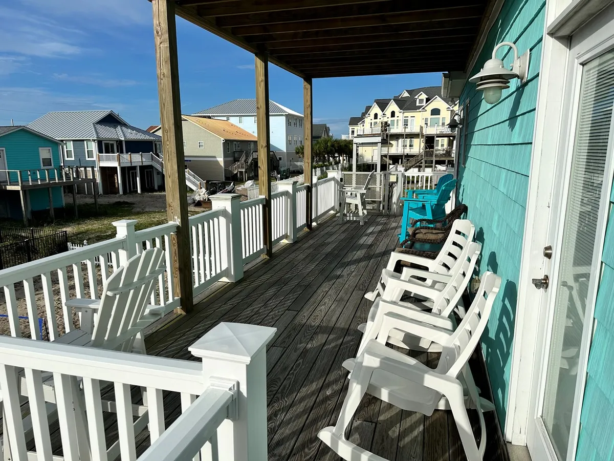 A tranquil outdoor deck scene with chairs and a table overlooking a blue house and expansive sky. It invites relaxation after a day of exploration, with the deck serving as a peaceful retreat to enjoy ocean views and fresh air.